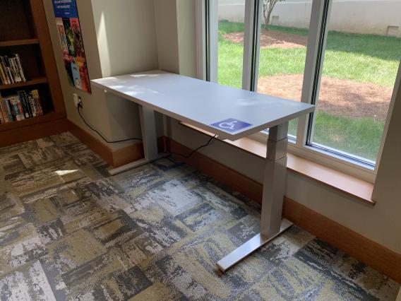 Handicap accessible table in front of a window in the libray's reading nook.